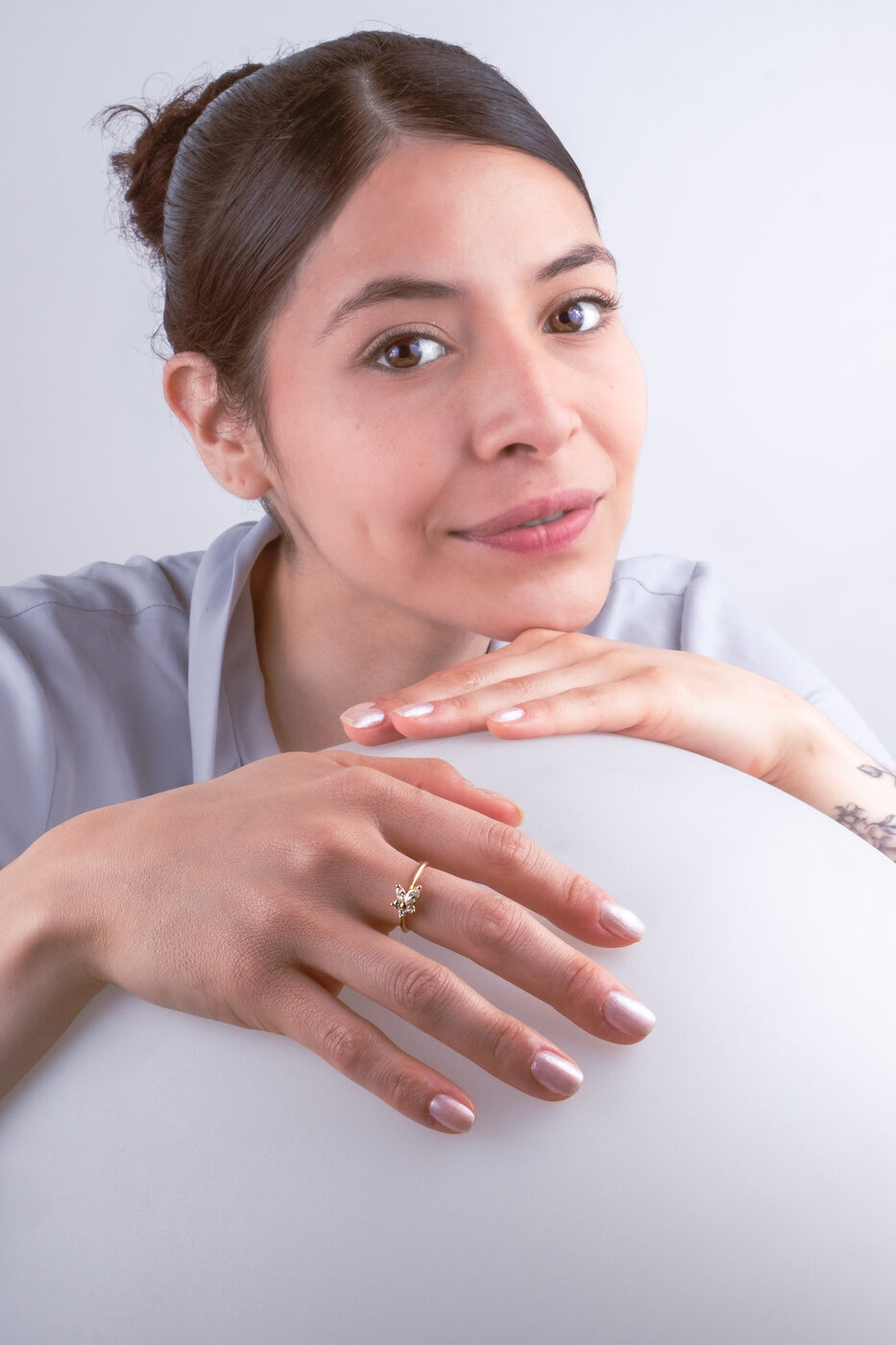 Bague de l'atelier portée, mains posées sur une sphère blanche